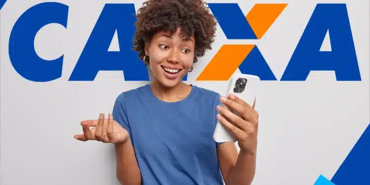 Jovem sorridente segurando smartphone com camiseta azul diante do logo da Caixa Econômica Federal