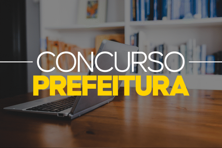 Notebook aberto sobre mesa de madeira com estante de livros ao fundo e texto concurso prefeitura