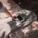 Uma mão tocando um smartphone e um caderno sobre um tecido, com sombras projetadas na superfície ao redor.