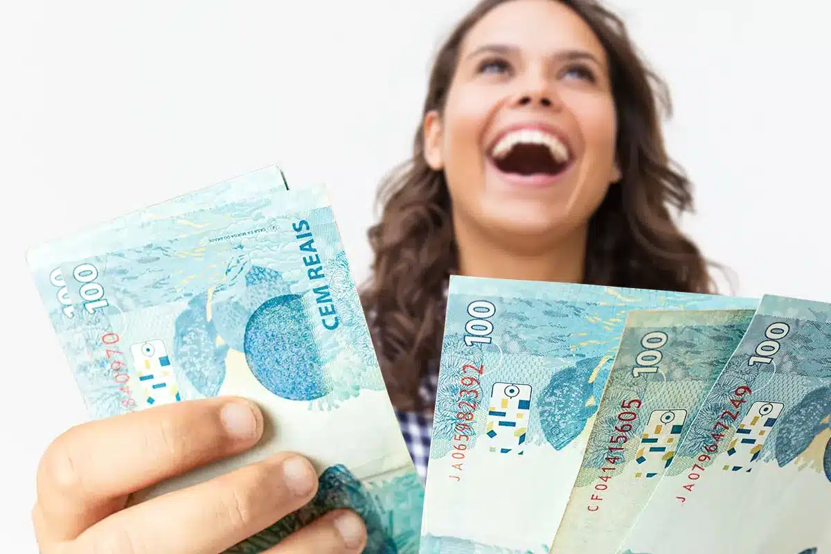Reajuste salarial e benefícios para aposentados do INSS em 2026. Pessoa sorrindo enquanto segura cédulas de 100 reais, representando o impacto do reajuste no salário mínimo para trabalhadores e aposentados do INSS.