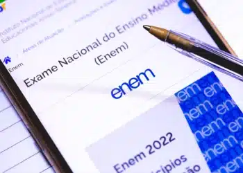 Foto de um smartphone exibindo a página do Exame Nacional do Ensino Médio (Enem), com uma caneta e cadernos ao lado, simbolizando a intensa preparação dos estudantes na última semana antes da prova de 2025.