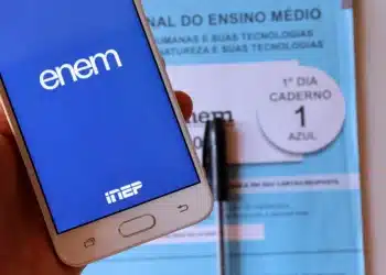 Celular com tela do aplicativo Enem e caderno azul do primeiro dia do exame ao fundo