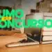 Mãos digitando em notebook ao lado de pilha de livros em biblioteca para concursos