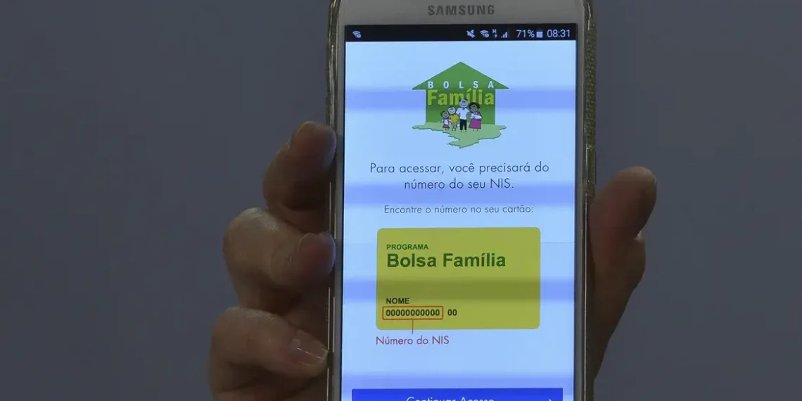 Consulta do Número do NIS para Bolsa Família no Celular Mão segurando celular Samsung mostrando tela de acesso com instruções para encontrar número do NIS do Bolsa Família