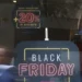 Letreiro luminoso anunciando Black Friday com desconto de 20% em loja com movimento de pessoas