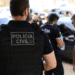Policiais civis com coletes e uniformes em operação junto a carros estacionados na rua