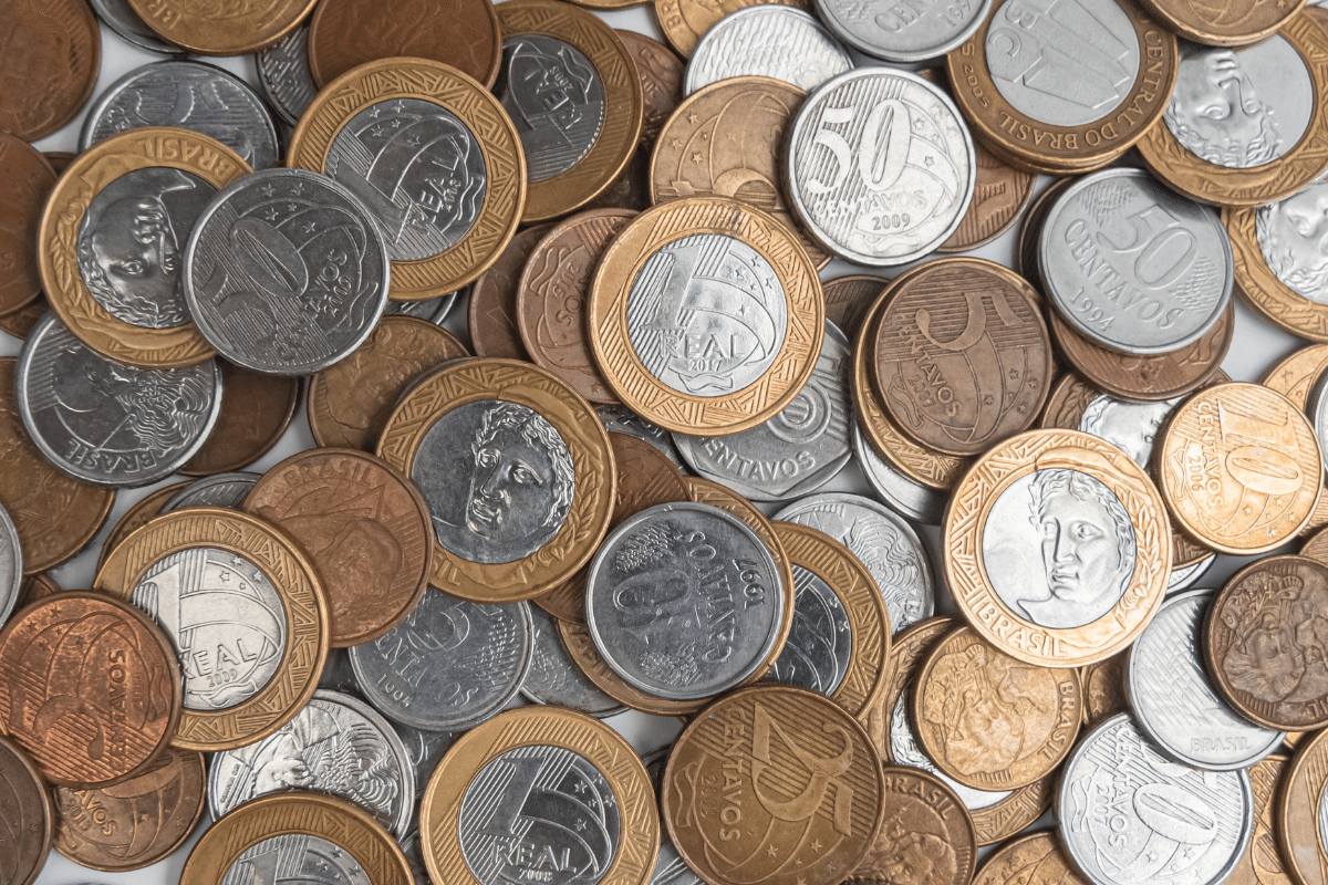 Diversas moedas brasileiras de centavos e reais sobre uma superfície branca