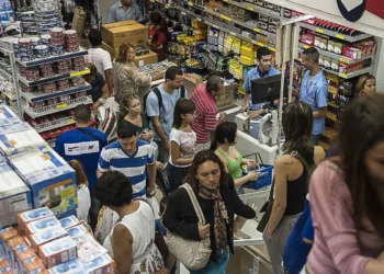 Consumidores fazem fila para pagar produtos em loja de materiais com prateleiras cheias