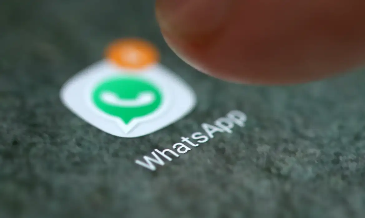 Foto de um dedo tocando no ícone do aplicativo WhatsApp com uma notificação na tela do celular