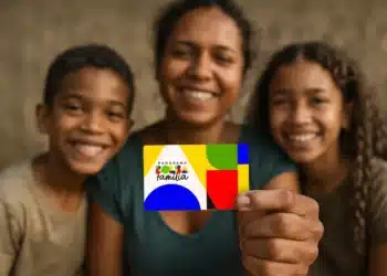 Mãe com dois filhos segurando cartão do Bolsa Família após inclusão de novas famílias no programa em dezembro