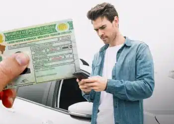 Imagem ilustrativa sobre a renovação automática e gratuita da CNH, com um homem segurando a CNH enquanto utiliza o celular.