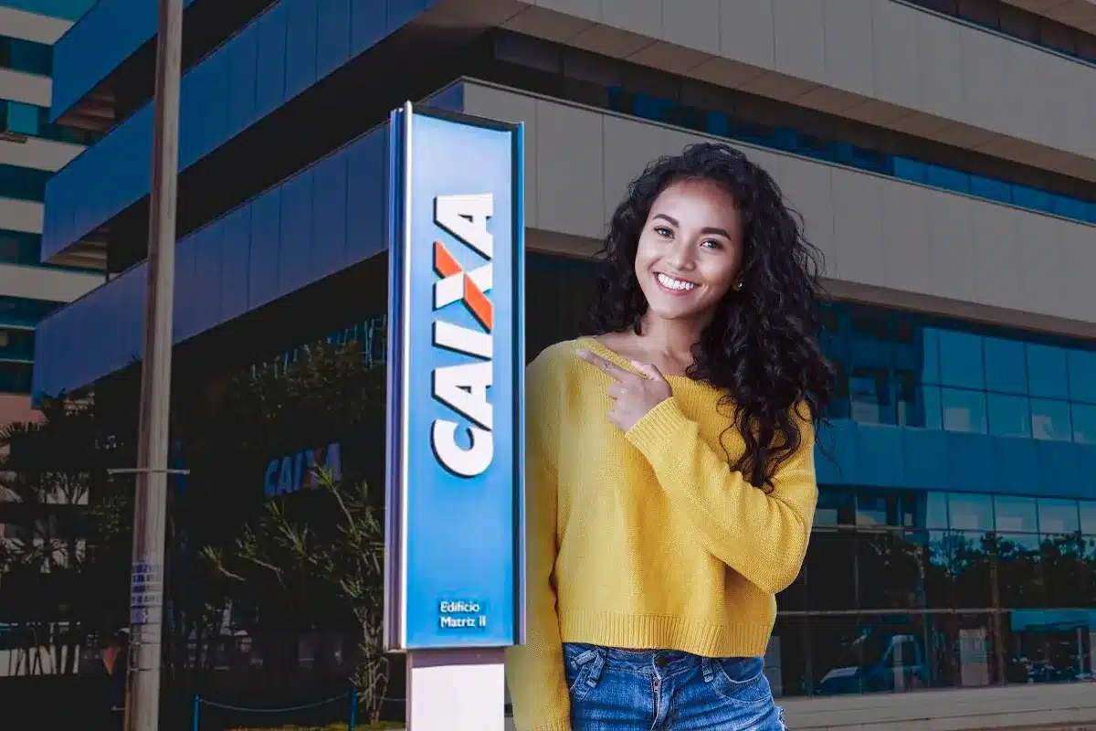 Concurso da CAIXA Candidata sorrindo ao lado de placa da CAIXA, simbolizando preparação para a prova do concurso do banco.