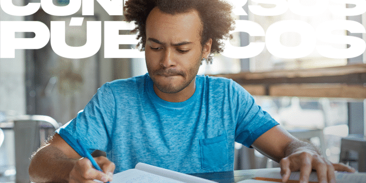 Homem concentrado estudando para concurso público com caderno e livros em ambiente de biblioteca.