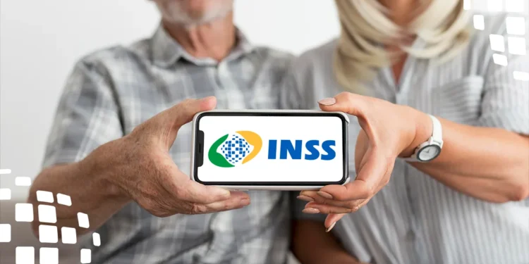 Casal de idosos segurando celular com o logo do INSS na tela em foco