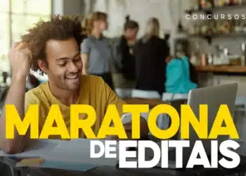 Candidato celebrando boa notícia ao conferir editais de concursos em notebook com materiais de estudo sobre a mesa.