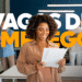 Candidata feliz analisando proposta de emprego em ambiente corporativo com equipe ao fundo ilustrando as 3 mil vagas disponíveis no Rio de Janeiro.