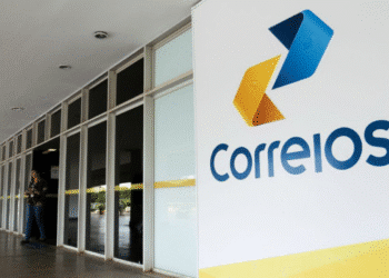 Entrada da agência dos Correios com logo colorida em destaque na parede branca.