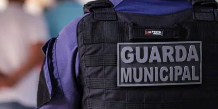 Detalhe do colete tático preto com placa "Guarda Municipal" na parte de trás do uniforme azul