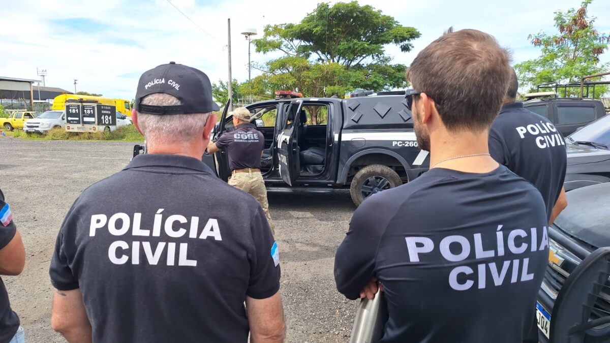 Policiais civis observam viatura preta da CORE, equipes reunidas em área externa com veículos estacionados ao fundo