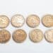 Quatro moedas brasileiras de 25 centavos alinhadas na parte superior e quatro na parte inferior, mostrando o anverso e o reverso. A imagem ilustra a busca por moedas raras com erro de cunhagem na numismática.