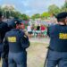 Três agentes da Guarda Civil Municipal observando multidão em evento ao ar livre em parque com lago
