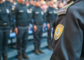 Guarda municipal em formação, com fardas pretas e distintivos evidenciados no ombro