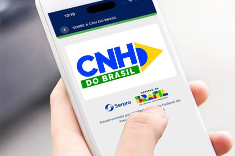 Foto em close de uma mão segurando um smartphone branco que exibe a logomarca colorida do aplicativo "CNH do Brasil" sobre um fundo branco limpo.