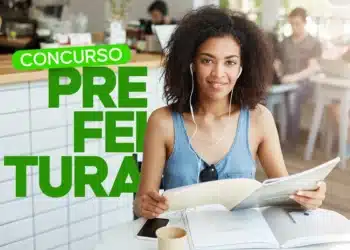 Mulher jovem estudando com fones de ouvido em cafeteria segurando material de leitura.