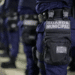 Agentes da Guarda Municipal enfileirados com uniforme azul e bolsa tática identificada.