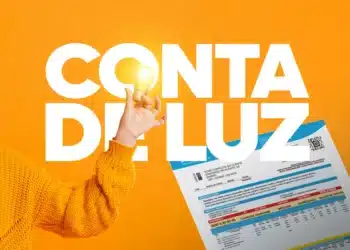 Pessoa segurando lâmpada acesa com fatura de conta de luz ao fundo em fundo laranja.