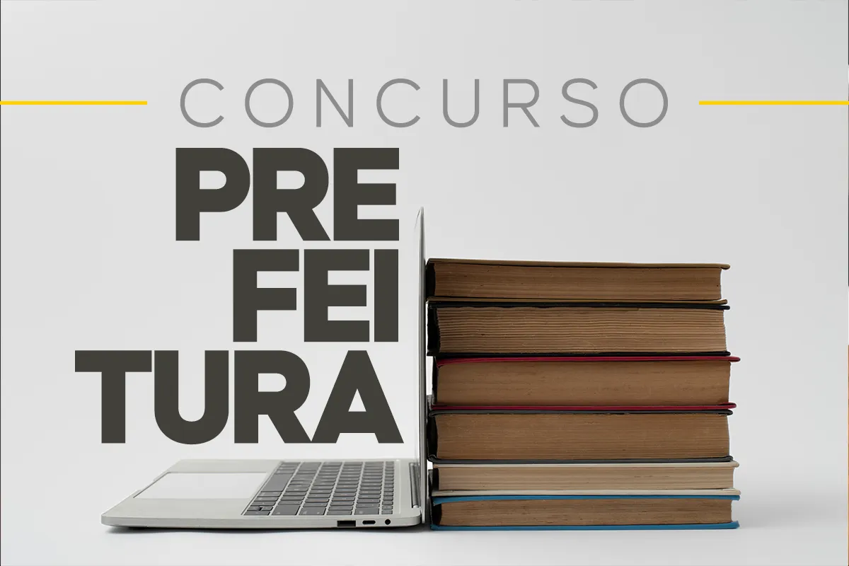 Notebook e livros empilhados representando preparação para concurso público municipal.