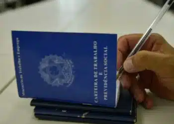 Carteira de Trabalho e Previdência Social sendo preenchida com caneta, representando o processo de solicitação do Seguro-Desemprego.