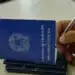 Carteira de Trabalho e Previdência Social sendo preenchida com caneta, representando o processo de solicitação do Seguro-Desemprego.