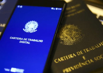 Celular com aplicativo Carteira de Trabalho Digital sobre documento físico da CTPS