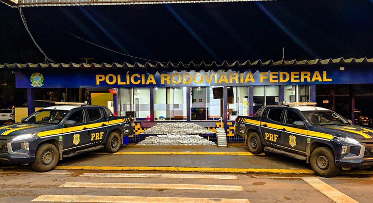 Viaturas da Polícia Rodoviária Federal estacionadas em frente à base noturna com letreiro iluminado