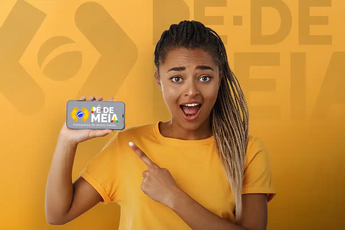 Uma pessoa sorrindo enquanto segura um celular mostrando o logo do Pé-de-Meia, indicando o procedimento para consultar a elegibilidade.