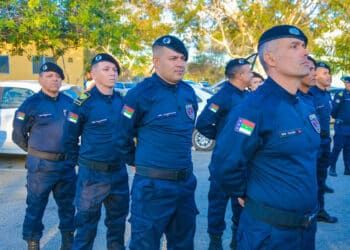 Grupo de guardas municipais alinhados em formação usando uniforme azul e boina preta em área externa.