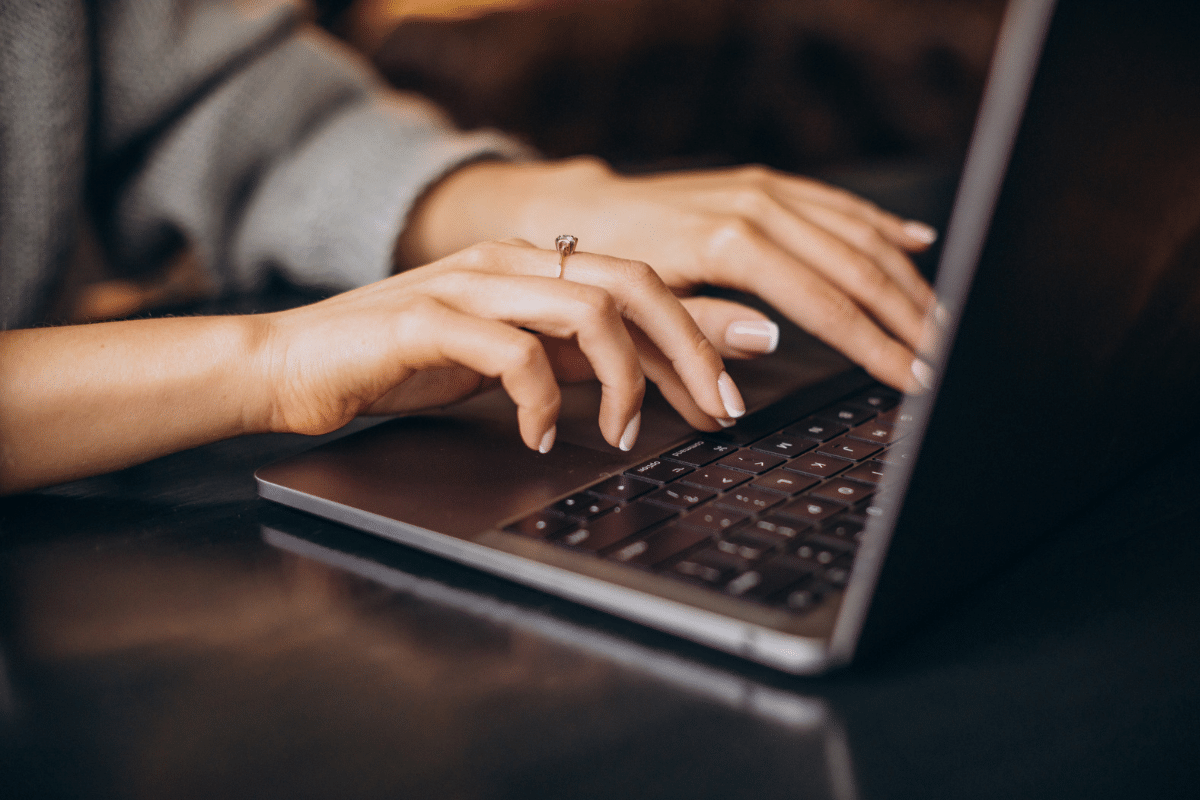 Mãos femininas digitando em notebook moderno, trabalho remoto