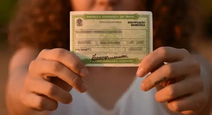 Título de Eleitor Pessoa segurando seu título eleitoral brasileiro, com identificação biométrica, mostrando o documento.