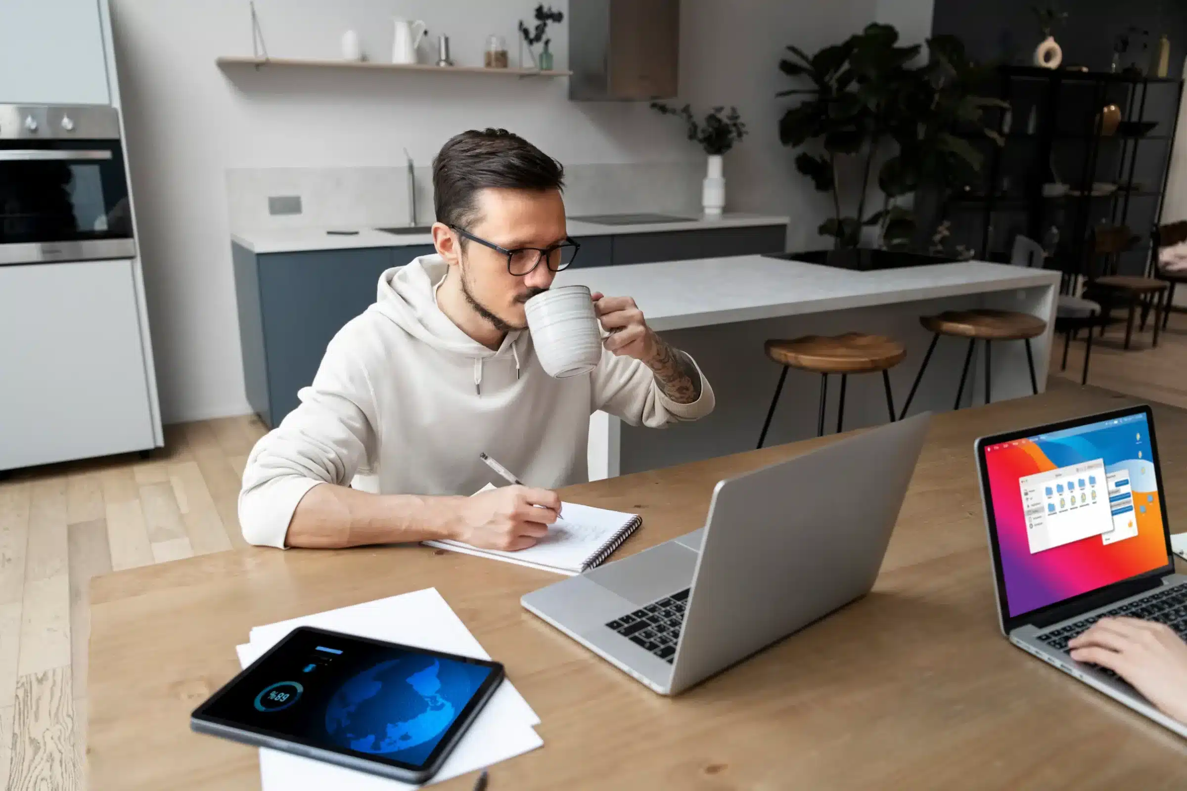 Homem trabalhando em home-office com laptop e tablet, aproveitando o avanço da tecnologia.