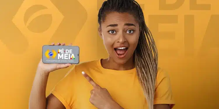 Estudante segura celular exibindo logo do Pé-de-Meia e aponta para a tela sorrindo, representando o pagamento do Pé-de-Meia em fevereiro e março.