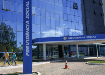 Pessoas caminhando em frente ao edifício espelhado da Previdência Social
