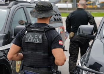 Policiais civis fardados próximos a viaturas durante ação no exterior