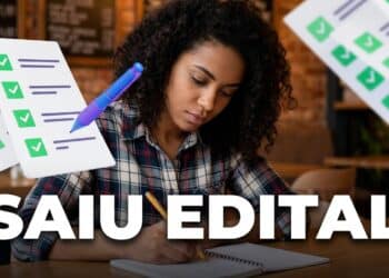 Mulher concentrada escrevendo em caderno, simulados de prova ao redor, ambiente de café.