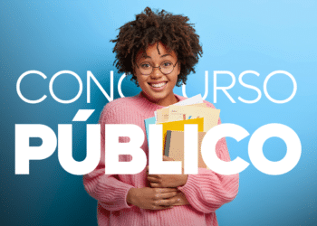 Jovem usando óculos e suéter rosa segura apostilas coloridas sorrindo em fundo azul