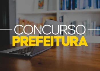 Notebook aberto sobre mesa exibe texto concurso prefeitura em destaque na biblioteca