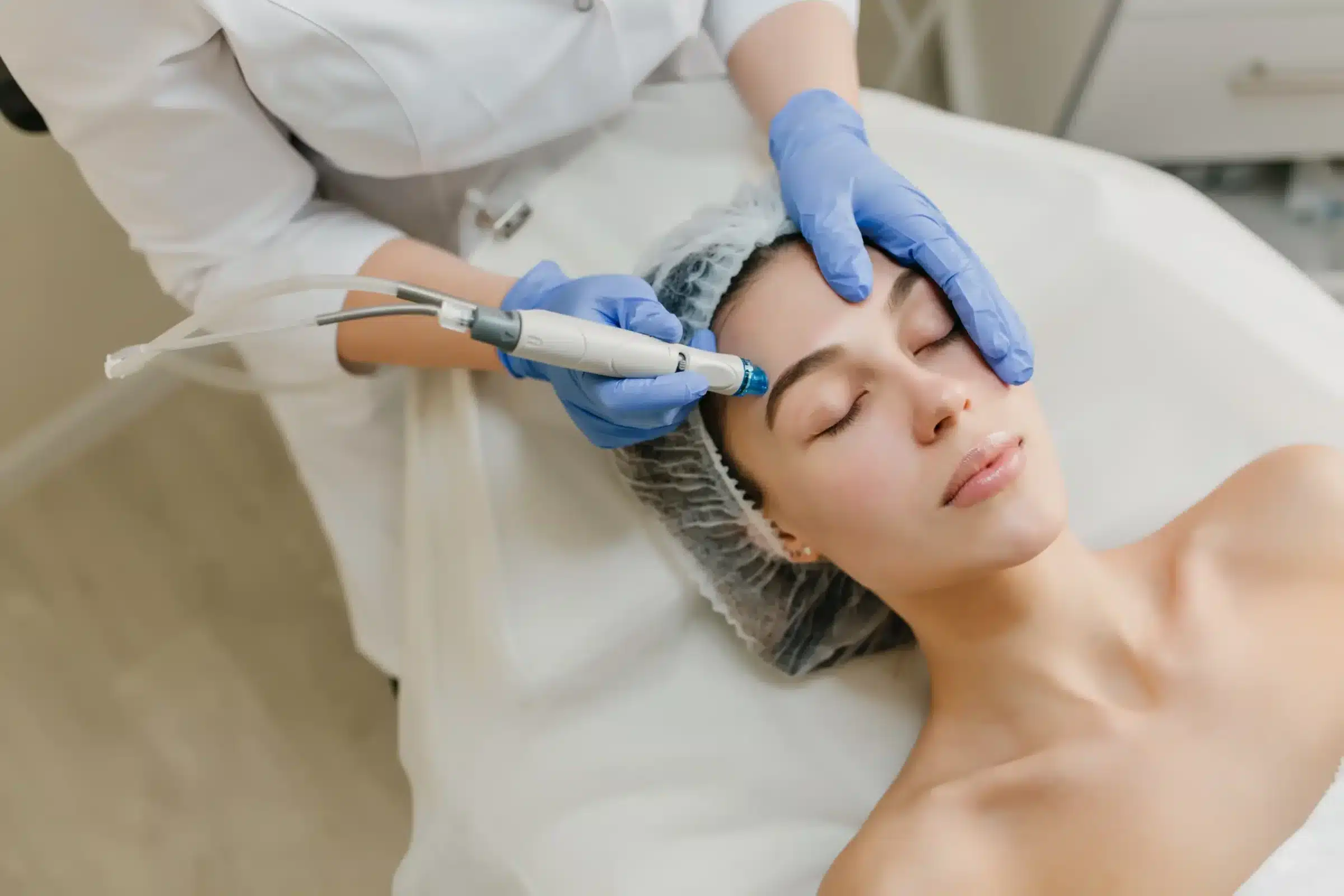 Profissional de estética aplicando um tratamento facial em uma cliente, com equipamentos modernos e cuidados de beleza.