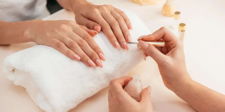 Profissional realiza serviço de manicure durante atendimento em salão de estética.