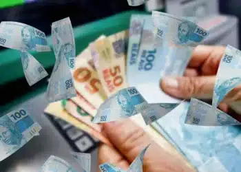 Notas de real nas mãos de beneficiário representando pagamento de benefícios do INSS com valores atualizados