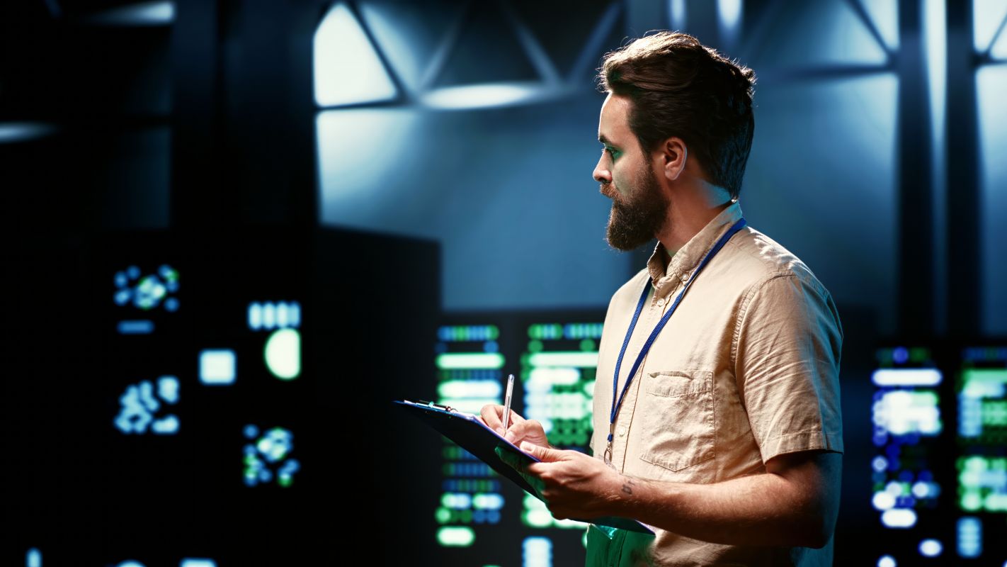 Técnico de tecnologia verificando equipamentos em data center responsável por infraestrutura de inteligência artificial. 